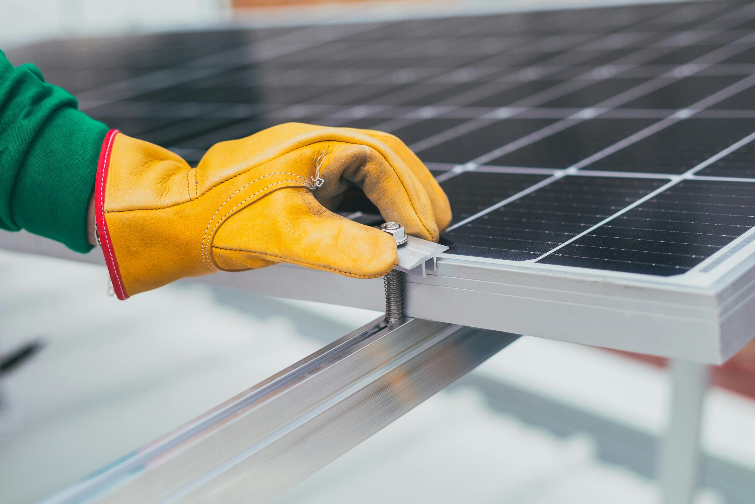 Solar installer's gloved hand repairing a solar panel